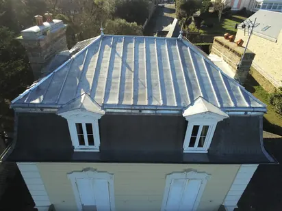 Vue au drone d'une villa à la Mansart à Saint-Lunaire : terrasson en zinc naturel à tasseaux, brisis en ardoise, lucarnes à frontons