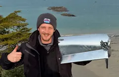 Willy Lambert, fondateur des Couvreurs Malouins, tient le membron d'angle en zinc et sa rose soudée, sur le chantier de Saint-Lunaire face à la mer